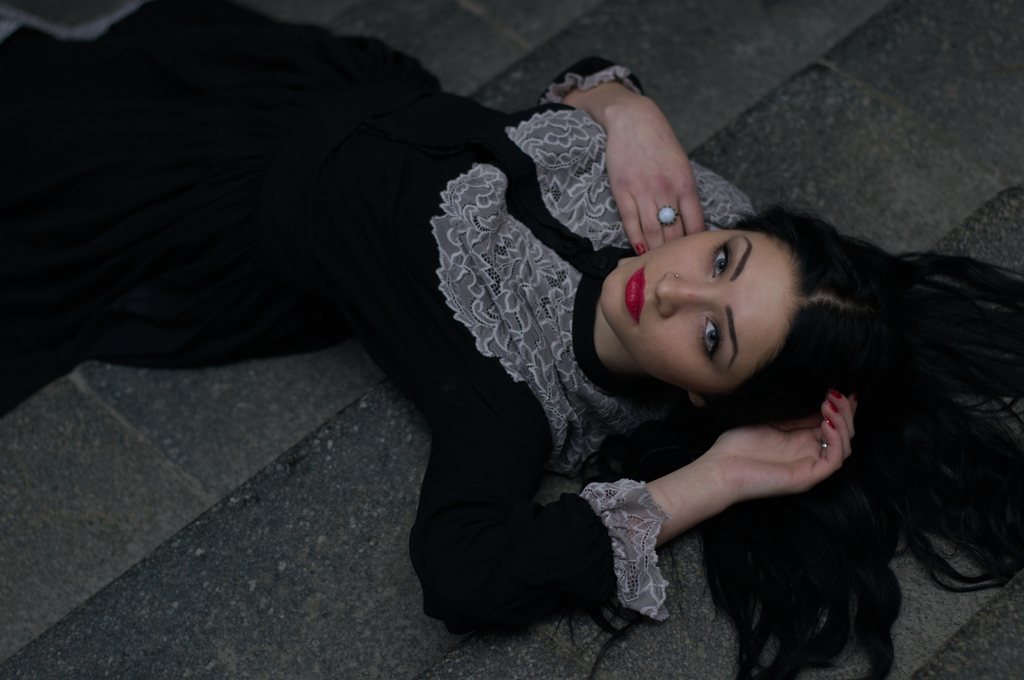 Portrait, femme brune allongée sur des pavés en robe de dentelle noire — raw file
