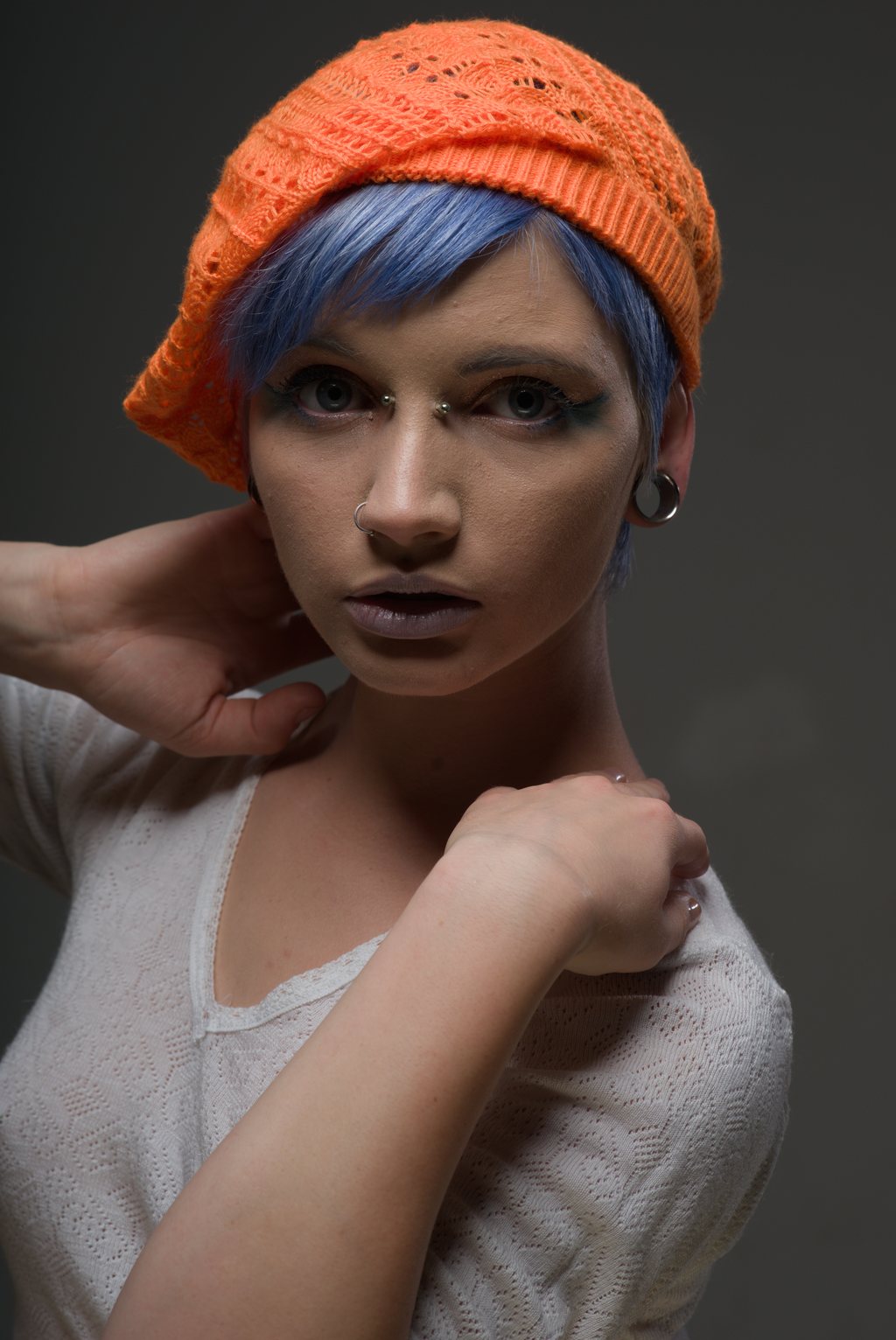 Portrait studio, cheveux bleus et bonnet orange sur fond sombre — raw file