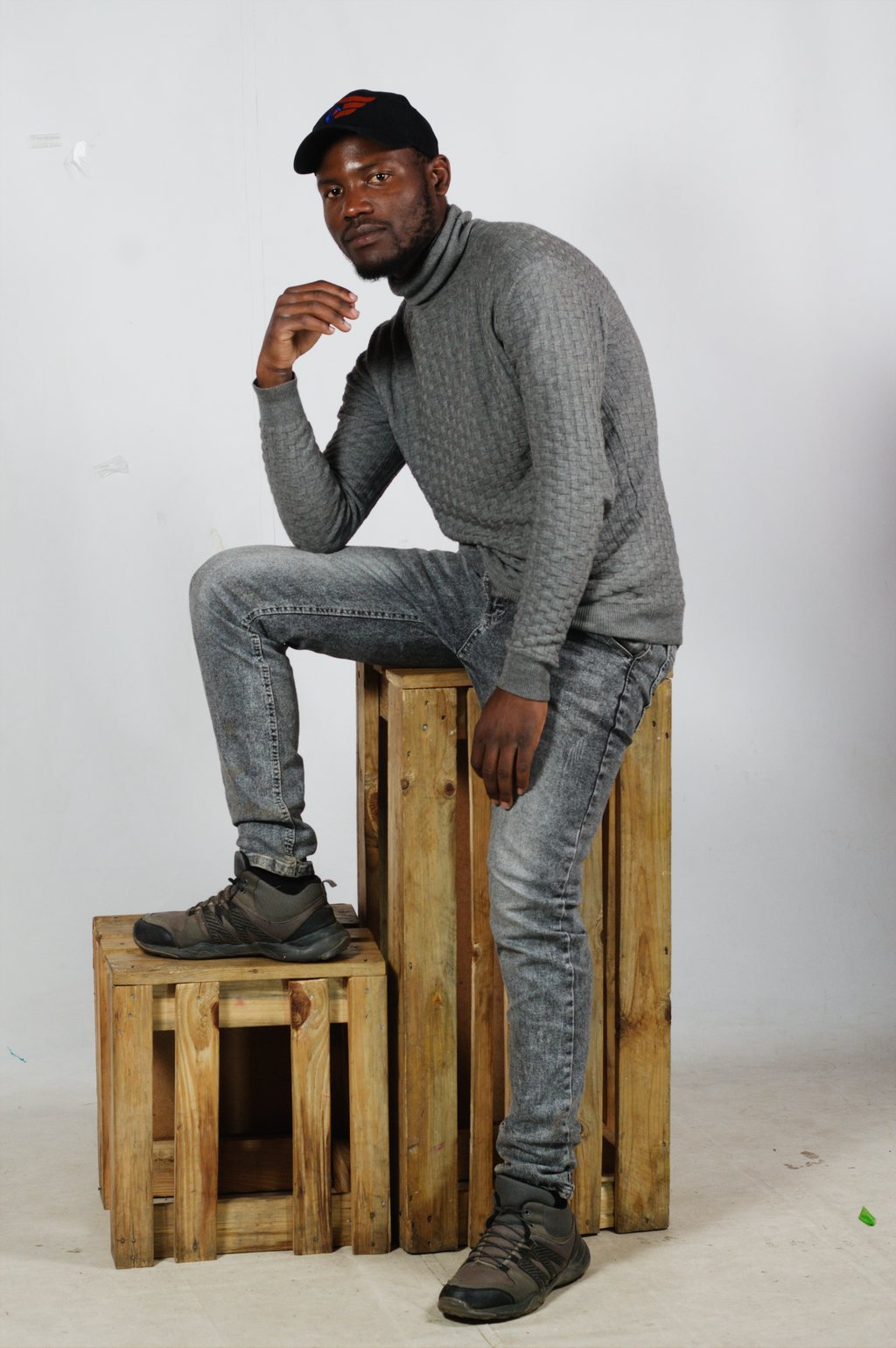 Portrait studio, homme en pull gris assis sur des caisses — neochrome version