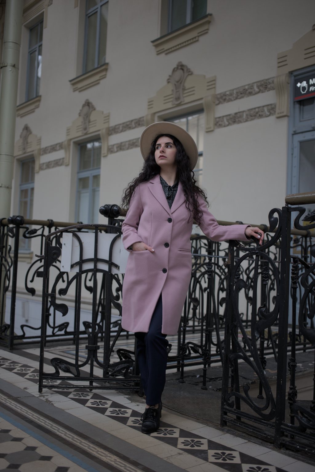 Femme en manteau rose et chapeau devant une façade Art nouveau — raw file
