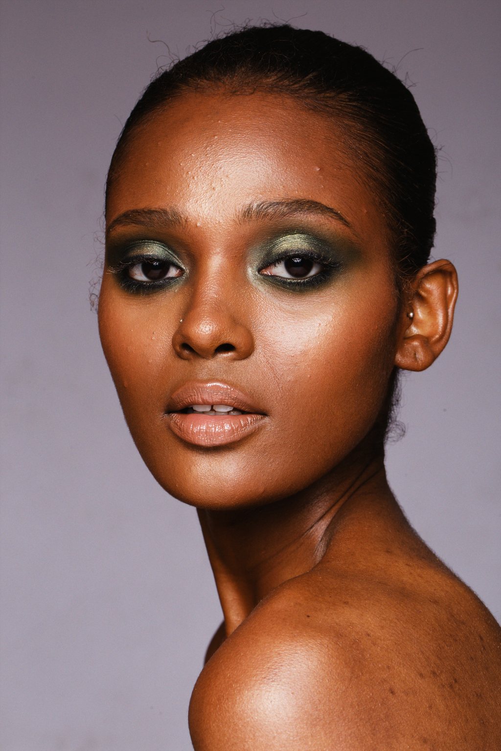 Portrait beauté en gros plan, femme noire au fard à paupières vert, peau lumineuse sur fond mauve — neochrome version