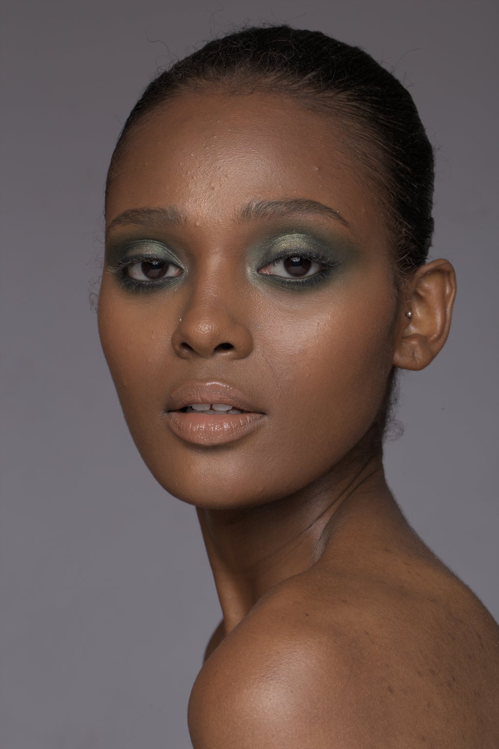 Portrait beauté en gros plan, femme noire au fard à paupières vert, peau lumineuse sur fond mauve — raw file