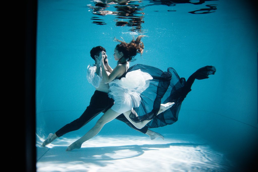 Couple dansant sous l'eau, robe de tulle blanche et chemise blanche, dans une eau turquoise — neochrome version