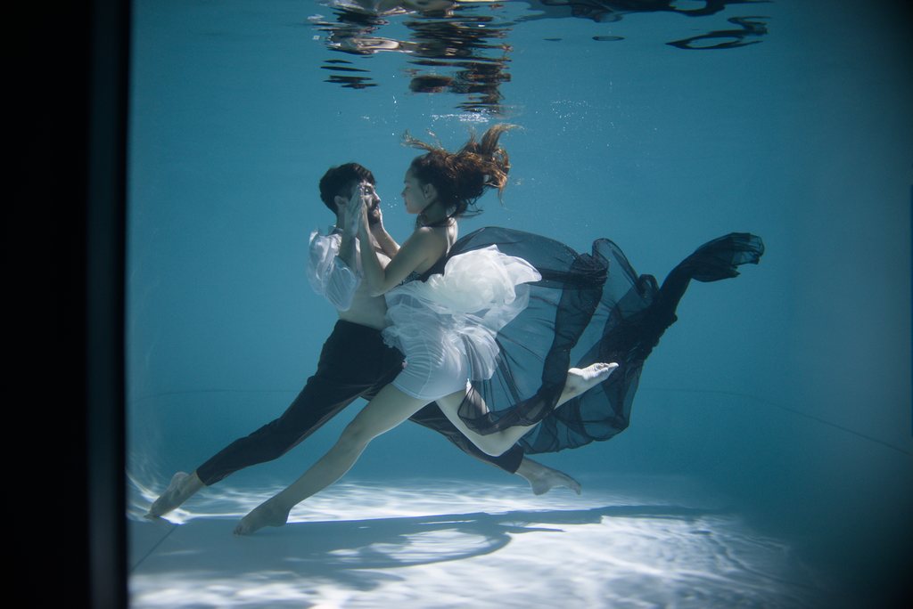 Couple dansant sous l'eau, robe de tulle blanche et chemise blanche, dans une eau turquoise — raw file